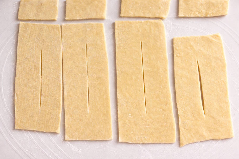 Krojenie ciasta na faworki krok po kroku Ciasto na faworki krojone w paski na blacie przed smażeniem