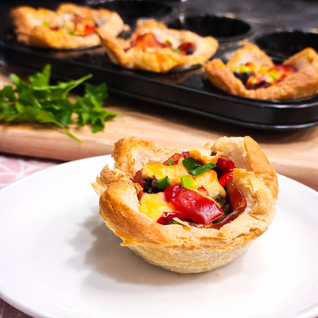 Wytrawne muffiny tostowe z pieczarkami i serem Domowe muffiny tostowe z pieczarkami, cebulą i roztopionym serem na talerzu