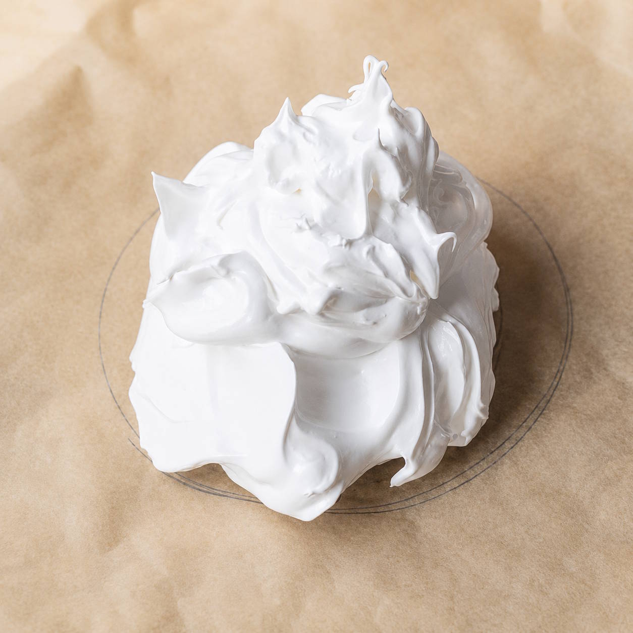Przygotowanie bezy Pavlova – zaznaczenie kształtu na papierze Papier do pieczenia z narysowanym kołem i nałożoną masą bezową