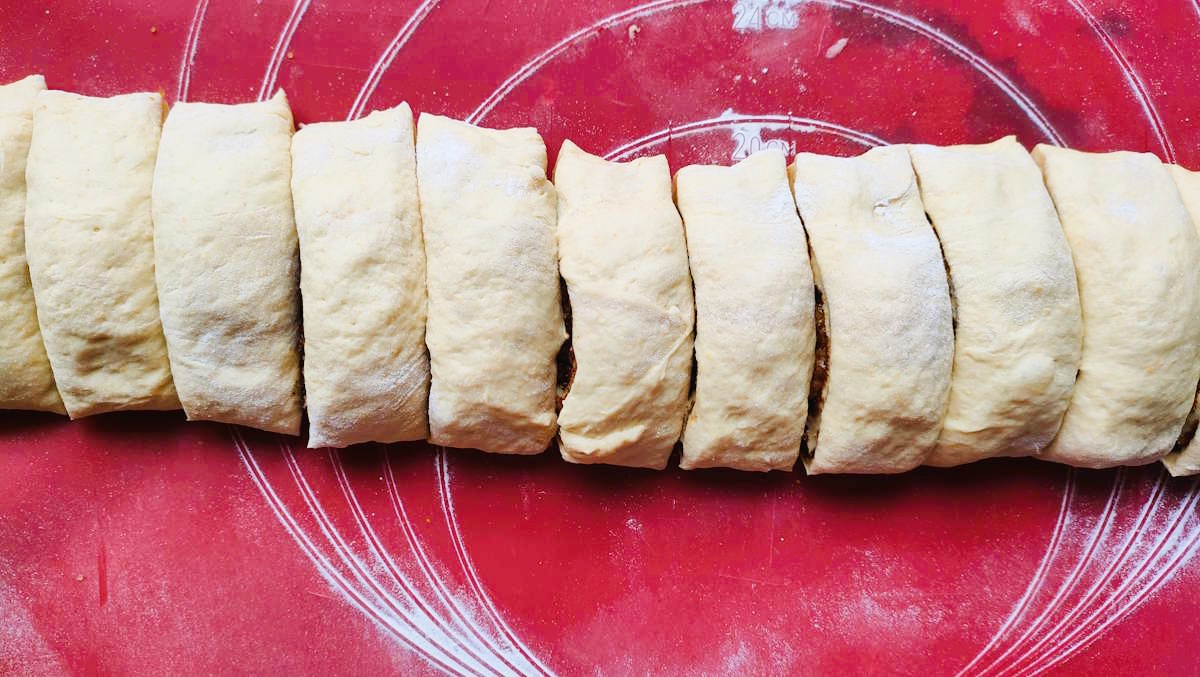 Rulon ciasta drożdżowego pokrojony na równe kawałki o grubości około 3 cm.